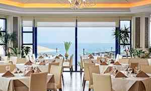 Restaurang med dukade bord, stora fönster och havsutsikt. (AI-genererad text)