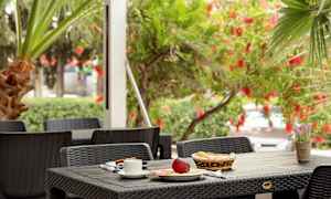 En utomhusbord med frukostmat och en blomkruka i en grön miljö. (AI-genererad text)