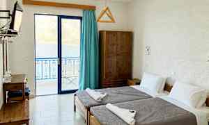 Ett hotellrum med två enkelsängar och utsikt över havet genom glasdörrar. (AI-genererad text)