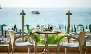 Två stolar vid ett bord med frukt och dryck, med utsikt över havet. (AI-genererad text)