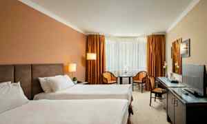 Hotellrum med två enkelsängar, ett bord, två stolar och en TV. (AI-genererad text)