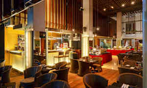 En restaurang med en buffé och sittplatser, inrett med trädetaljer och varm belysning. (AI-genererad text)