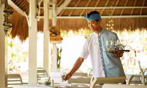 En servitör medett serveringsfat och glas förbereder ett bord på en restaurang. (AI-genererad text)