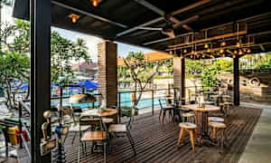 En uteservering med bord och stolar, samt en pool i bakgrunden. (AI-genererad text)