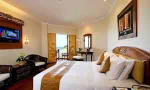 Ett hotellrum med en dubbelsäng, skrivbord, sittgrupp och en balkong med utsikt. (AI-genererad text)