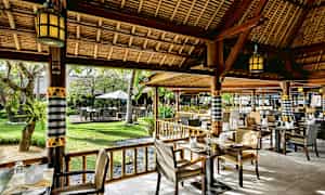 En restaurang med sittplatser utomhus, omgivet av grönska. (AI-genererad text)