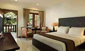 Ett hotellrum med dubbelsäng, sittgrupp och fönster med utsikt mot grönska. (AI-genererad text)