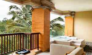 En terrass med panoramautsikt över grönska, med sittmöbler och en jacuzzi. (AI-genererad text)