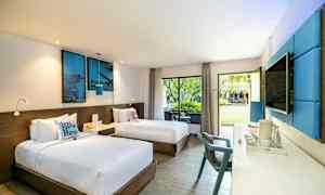 Ett hotellrum med två enkelsängar, modern inredning med blå detaljer, och stora fönster som vetter mot en trädgård. (AI-genererad text)