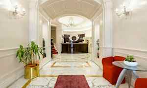 Ett elegant hotellobby med marmorgolv, en reception med mörk träpanel och en elegant ljuskrona. (AI-genererad text)