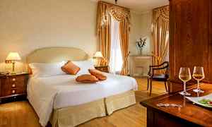 Ett elegant hotellrum med dubbelsäng, dekorerade kuddar, och träinredning. (AI-genererad text)