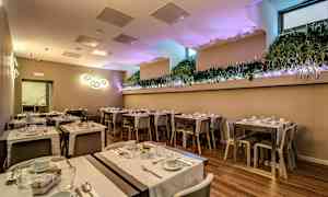 Uppdukat rum med bord och stolar, dekorerat med växter och ljuskällor. (AI-genererad text)