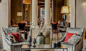 Två fåtöljer med kuddar framför ett bord med dekorationsföremål, i en elegant inredd miljö. (AI-genererad text)