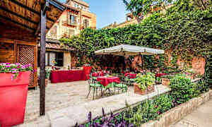 Uteplats med bord och stolar samt grönska. (AI-genererad text)