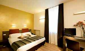 Ett hotellrum med en dubbelsäng, skrivbord och TV. Rummet har ljusa väggar och ett stort fönster med mörka gardiner. (AI-genererad text)