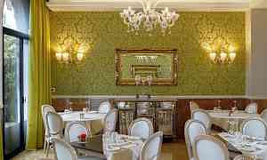 En restaurang med gröna väggar, stilfulla stolar och bord med dukar. (AI-genererad text)