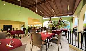 Uteservering med dukade bord och röda bordsdukar, stolar och en grön vägg i bakgrunden. (AI-genererad text)