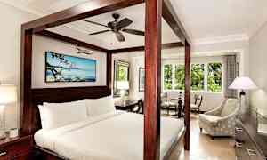 Ett hotellrum med en himmelssäng, en sittgrupp och ett stort fönster. (AI-genererad text)