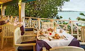 Ett dukat bord på en terrass med utsikt över havet. (AI-genererad text)