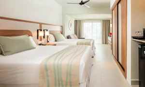 Hotellrum med två sängar, ljus inredning och stora fönster. (AI-genererad text)