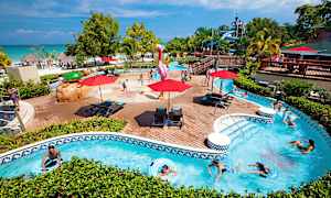 Poolområde med barn som leker samt personer som simmar i en omgivande strömmande pool. (AI-genererad text)