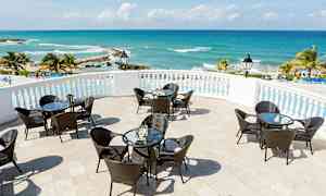 Terrass med bord och stolar, havsutsikt och palmträd. (AI-genererad text)