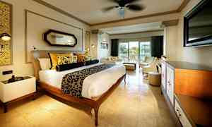 Ett hotellrum med en dubbelsäng, inbjudande sittgrupp och balkong med utsikt. (AI-genererad text)