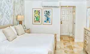 Ett ljust och stilrent sovrum med en dubbelsäng, väggkonst och en dörr. (AI-genererad text)