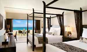 Hotellrum med två sängar med himmelssängar och utsikt över havet från en balkong. (AI-genererad text)