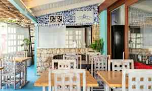 Restaurang med träbord och stolar samt dekorerad vägg med blått kakel. (AI-genererad text)