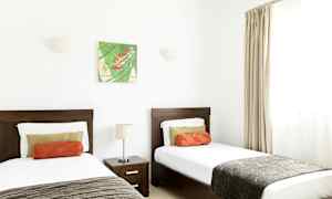 Rum med två enkelsängar, en nattduksbord och väggdekoration. (AI-genererad text)