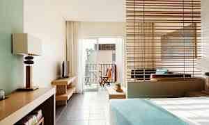 Ett hotellrum med modern inredning och utsikt mot en balkong med utemöbler. (AI-genererad text)