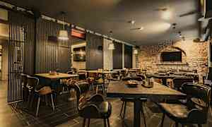 En restaurang med träbord och stolar samt tegelväggar. (AI-genererad text)
