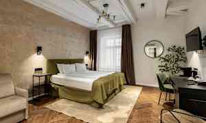 Ett hotellrum med en dubbelsäng, sängbord, en skrivbordshörna och en spegel på väggen. (AI-genererad text)