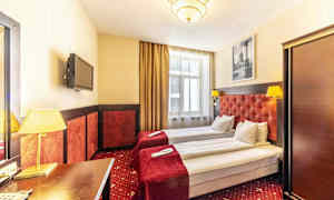 Hotellrum med två enkelsängar, röda sängöverkast och lampor. (AI-genererad text)