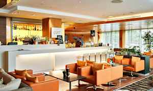 En modern och elegant lounge med en vit bardisk, bakgrundsbelysta spritflaskor och bekväma orange fåtöljer. (AI-genererad text)