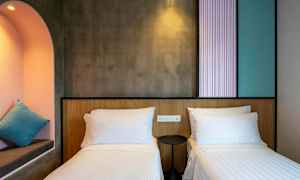 Ett hotellrum med två enkelsängar, en liten rund nattduksbord, och en inbyggd alkova med en kudde. (AI-genererad text)