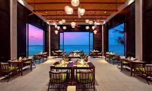 Bild av en restaurang med havsutsikt och färgglad kvällshimmel. (AI-genererad text)