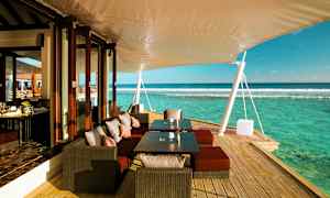 Utomhusterass med sittplatser, bord och utsikt över havet. (AI-genererad text)