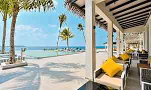 En utomhusterrass med sittmöbler och en pool med utsikt över havet. (AI-genererad text)