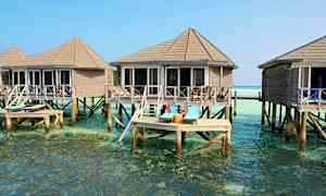 Bilden visar bungalows på pålar över klart vatten, med solstolar på en terrass. (AI-genererad text)