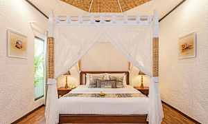 Ett sovrum med en himmelssäng och dekorativa kuddar. (AI-genererad text)