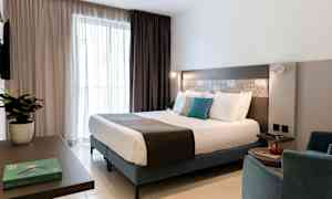 Ett modernt hotellrum med en dubbelsäng, sittmöbler och inredningsdetaljer. (AI-genererad text)