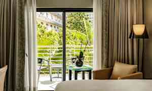 Hotellrum med utsikt mot en grönskande balkong. (AI-genererad text)