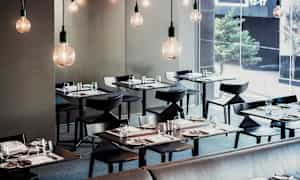 En modern restaurang med elegant dukade bord och hängande glödlampor. (AI-genererad text)