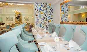 En elegant matsal med ljusblå stolar och dekorerade bord. (AI-genererad text)