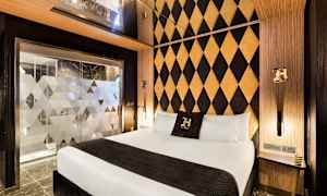 Hotellrum med modern inredning, dubbelrumssäng och dekorativt mönstrad vägg. (AI-genererad text)