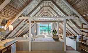 Rum med tak i träpanel och utsikt mot havet genom glasdörrar. (AI-genererad text)