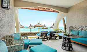 En terrass med blå sittmöbler och utsikt mot havet med parasoller. (AI-genererad text)