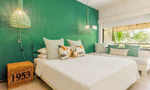 Ett sovrum med grön vägg, vit säng och dekorativa kuddar. (AI-genererad text)